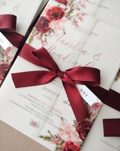 the wedding stationery is wrapped in red satin ribbon and tied with a matching bow