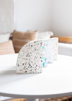 three coasters sitting on top of a white table in front of a couch and chair