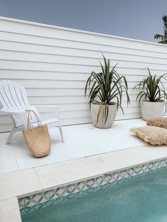 a white chair sitting on top of a pool next to a planter filled with potted plants