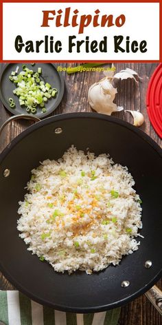 a pan filled with rice and vegetables on top of a wooden table next to other plates