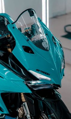 the front end of a blue motorcycle parked in a garage with no one around it