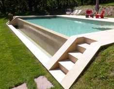 an empty swimming pool with steps leading up to the bottom and green grass around it