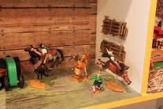 several toy figurines are displayed on a shelf in front of a wooden wall