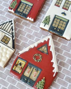 three decorated gingerbread houses sitting on top of a brick floor next to each other