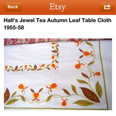 the table cloth has been embroidered with orange flowers and leaves on it, along with other decorative items