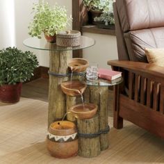 a wooden table topped with two vases filled with water next to a brown couch