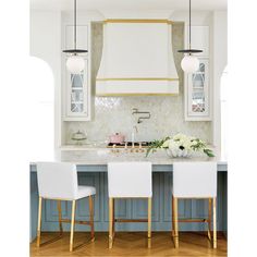 a kitchen with blue cabinets and white countertops, gold trimmings and stools