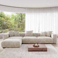 a living room with a large sectional couch and coffee table in front of the window