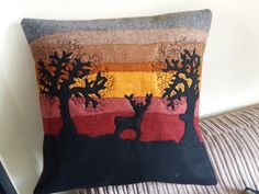 a decorative pillow with an image of two deer in the sunset and trees on it