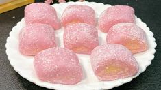 pink donuts on a white plate with sprinkles and flowers in the background