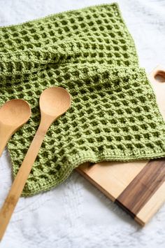 two wooden spoons and a green crocheted dishcloth