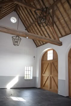 an empty room with two large wooden doors in the center and one light hanging from the ceiling