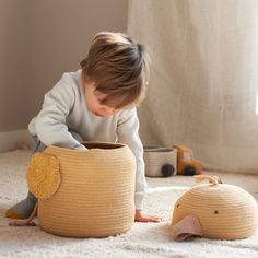 a small child playing with a stuffed animal in a crocheted basket on the floor