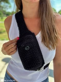 a woman wearing a white tank top holding a black crocheted purse