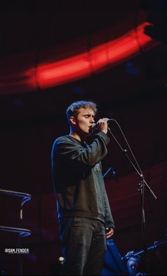 a man standing in front of a microphone on stage