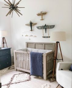 a baby's room with a crib, rocking chair and airplane decorations on the wall