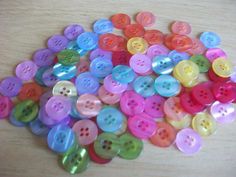 a pile of colorful buttons sitting on top of a wooden table