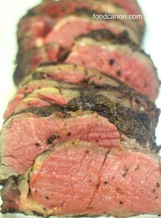 sliced steak on a white plate with green garnish