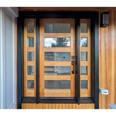 a wooden door with glass panels and black trim on the side walk leading to an entrance