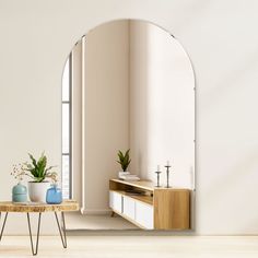 an arch shaped mirror in a living room next to a table with two vases on it