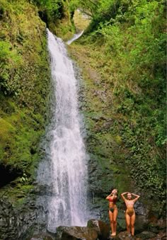 two women standing in front of a waterfall