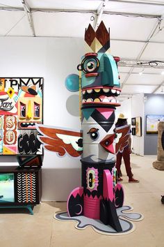 an art exhibit with sculptures and paintings on the walls, including totems in different colors