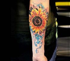 a sunflower tattoo on the left arm and shoulder with watercolor paint splatters all over it