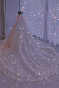 a woman in a wedding dress standing next to a window with sparkling lights on it