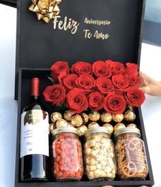 a box filled with lots of red roses next to a bottle of wine and chocolates