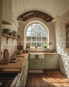 a kitchen with an arched window and wooden flooring in front of the counter top