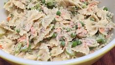 a bowl filled with pasta and peas on top of a wooden table