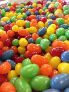 there are many different colored candy balls in the bins, and they look like jelly beans