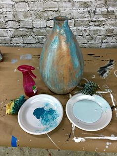 two white plates sitting on top of a wooden table next to a blue and brown vase