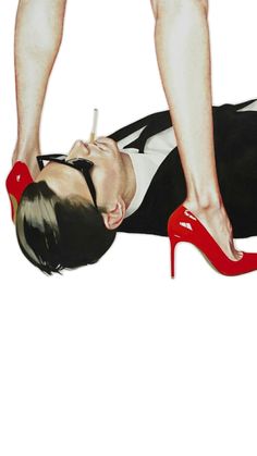 a woman laying on the ground with her legs crossed and red high heels in front of her