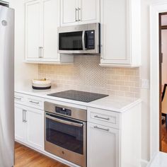 a kitchen with white cabinets and stainless steel appliances