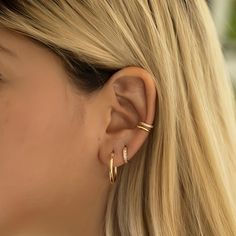 a close up of a woman's ear wearing gold earrings