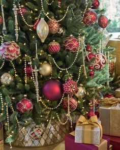 a christmas tree decorated with red and gold baubles, ornaments and bows on it