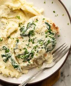 a white plate topped with mashed potatoes and spinach covered in gravy