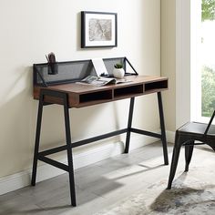 a desk with a chair next to it in front of a window and a painting on the wall