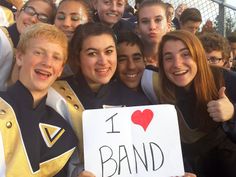 a group of young people standing next to each other holding a sign that says i love band