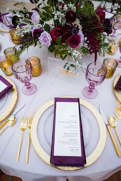 the table is set with purple and gold place settings, silverware, and flowers