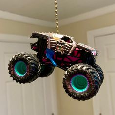 a toy monster truck hanging from a chain with lights on it's front wheels