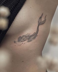 a black and white photo of a woman's stomach with a fish tattoo on it