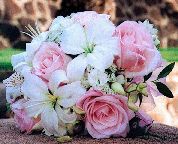 a bouquet of pink and white flowers sitting on top of a stone wall in front of a building