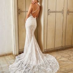 a woman in a wedding dress leaning against a wall with her back to the camera