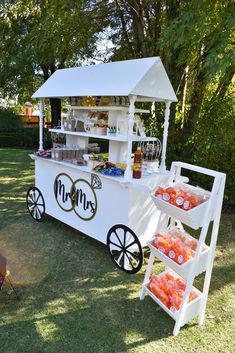 an ice cream cart is set up in the grass with oranges and drinks on it