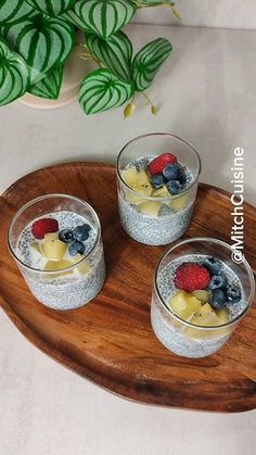 three glasses filled with fruit on top of a wooden tray