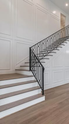 an empty room with white walls and wood flooring, stairs leading up to the second floor