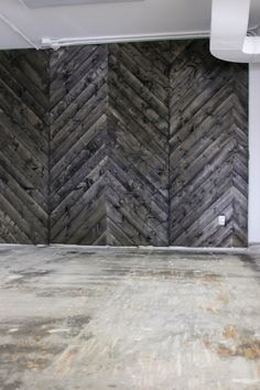 an empty room with wood paneling on the wall and concrete floor in front of it