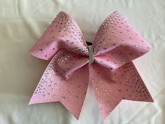 a pink bow with silver sequins is laying on a white sheet and it looks like something out of space